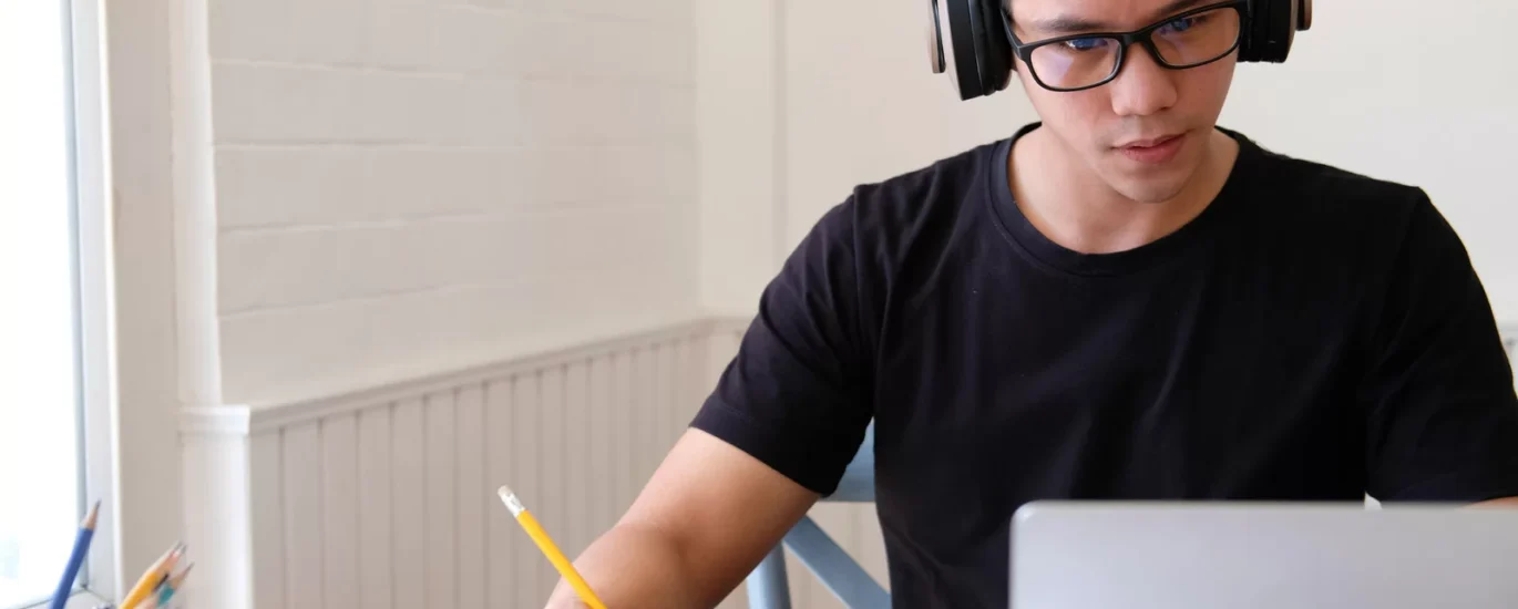 Young person studying at a clean desk with headphones on, showing how to train your brain to concentrate in a distraction-free environment