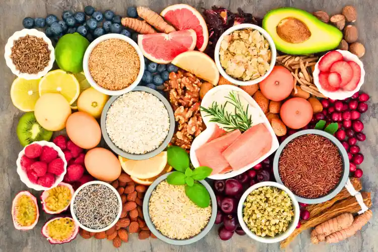 A top-down view of a wooden table with chamomile tea, salmon, yogurt, berries, and leafy greens arranged beautifully as calming foods for anxiety relief.